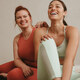 dwie uśmiechnięte kobiety w stroju sportowym: legginsy i staniki sportowe