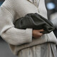 kobieta w beżowym rozpinanym swetrze z czarną torebką w ręce